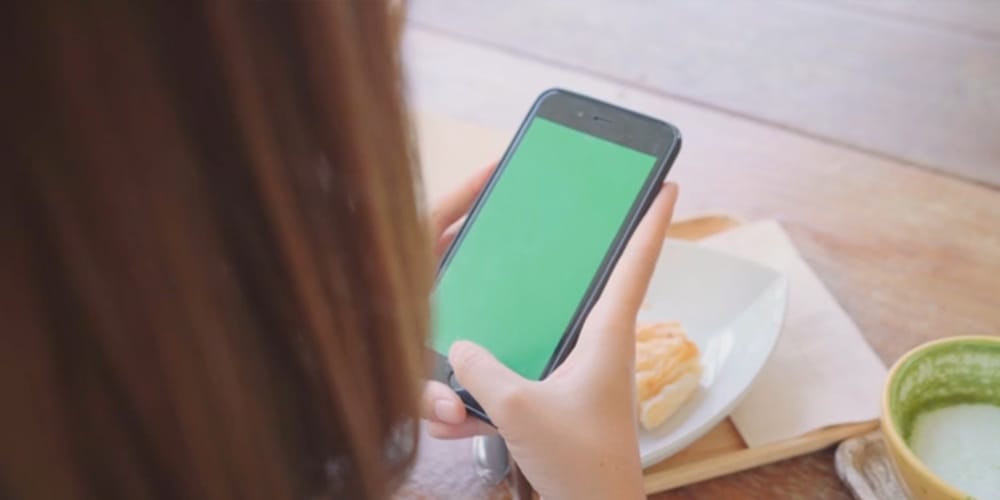 woman using black mobile phone device with green screen